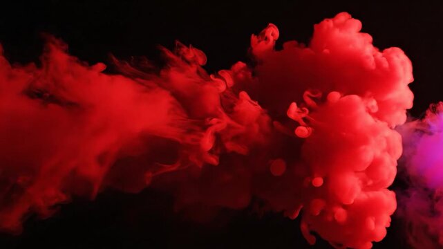 Vibrant red and pink smoke plumes gracefully spread and mix in dark water