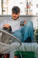 young man having coffee with his pet on a terrace
