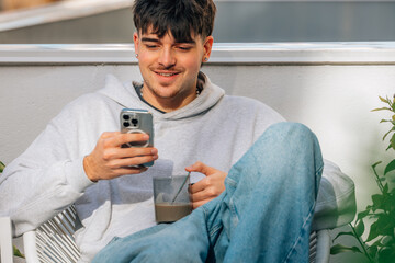 young man with mobile phone drinking coffee on the terrace