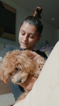 Peaceful scene of woman softly petting her puppy on sofa