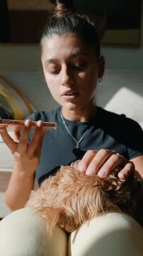 Young woman gently strokes her fluffy dog as she talks calmly