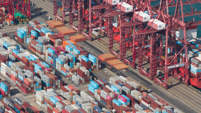 New Territories, Hong Kong - 15 February 2026: Aerial view of a sea of stacked, multicolored shipping containers beneath towering red cranes, creating a vibrant, industrial mosaic.