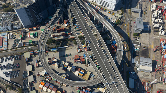 New Territories, Hong Kong - 15 February 2026: Aerial view of intertwining highways and stacked containers, a tapestry of concrete and steel against a backdrop of industrial activity.