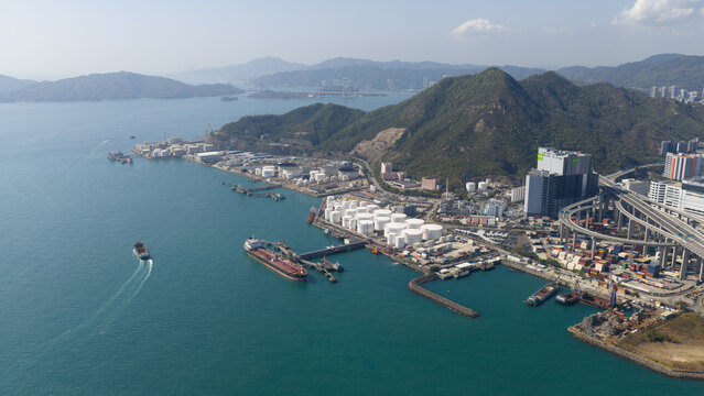 New Territories, Hong Kong - 15 February 2026: Aerial view of the industrial area where storage tanks meet the sea, a tapestry of maritime activity against the backdrop of lush mountains.