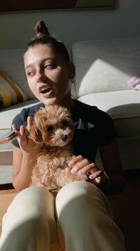 Asian woman communicates on phone while puppy rests comfortably in her lap