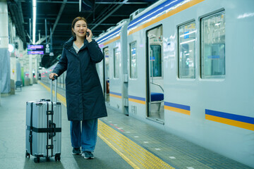 Obraz premium Asian Woman Talking on Phone at Train Station Platform