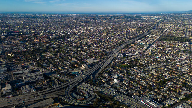 Los Angeles, United States - 27 February 2026: Aerial view of a sprawling cityscape, where concrete highways weave like ribbons through a dense tapestry of buildings under a vast, clear sky.