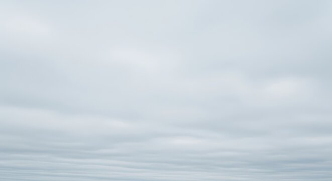 A vast expanse of pale gray sky filled with dense, uniform clouds, creating a dreary and overcast natural background texture and atmosphere, copy space, texture, gloomy