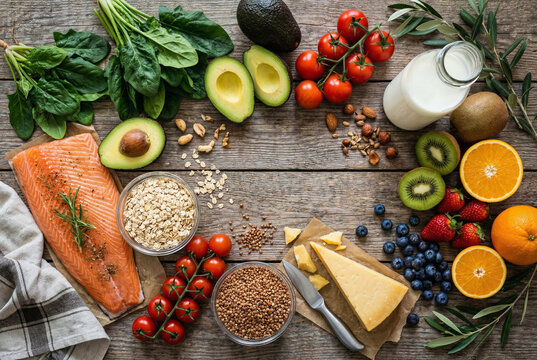 Healthy food frame with salmon, vegetables, fruit, nuts and milk on wooden table. Top view flat lay of fresh organic ingredients for diet.