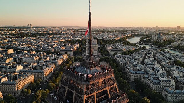 Tourists visit iconic iron lattice tower at sunset overlooking cityscape in Paris, France