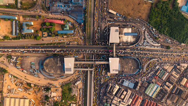 Lagos, Nigeria - 24 February 2026: Aerial view of the snaking traffic around the Oshodi pedestrian overpass, a stark contrast to the surrounding buildings and greenery.