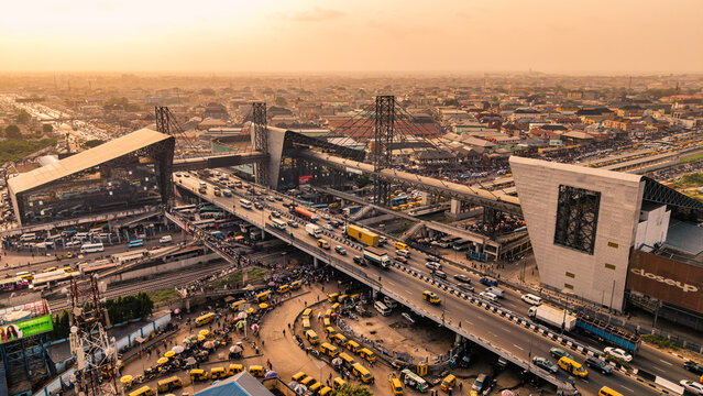 Lagos, Nigeria - 24 February 2026: Aerial view of the bustling Oshodi pedestrian overpass, a vibrant tapestry of yellow taxis swirling below the elevated highway.
