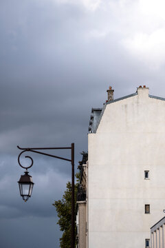 Minimal building facade architecture on a white wall with streetlamp under cloudy sky in Paris France creating a quiet urban exterior composition
