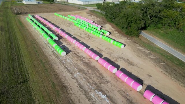 Drone slowly descends revealing long parallel cotton module rows stored on agricultural land near Headland in Henry County, Alabama within the Wiregrass region during autumn cotton harvest logistics