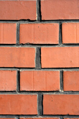 Obraz premium A close up of a red brick wall featuring rectangular bricks with smooth surfaces and dark grey mortar joints including some faint white graffiti