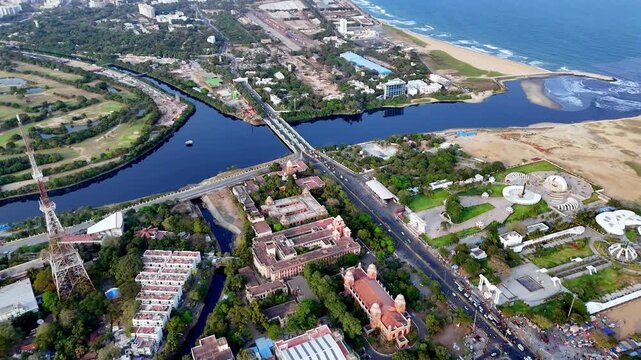 Cinematic aerial view of Chenani of the Anna and Kalaignar Memorials alongside the MGR and Jayalalithaa Memorials &mdash; iconic arches and landscaped grounds set against Marina Beach and the Bay of Bengal.