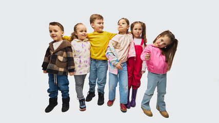 Fototapeta premium Group of children standing together wearing colorful mid season kids fashion outfits in studio. Concept of children clothing promotion, seasonal apparel collection and modern kids fashion campaign.