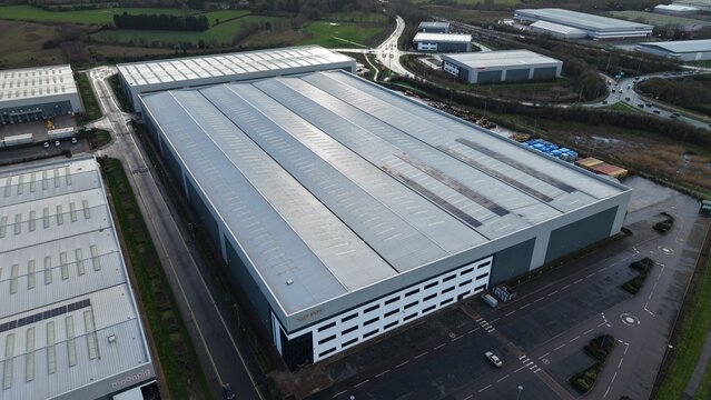 Tamworth, United Kingdom - 21 February 2026: Aerial view of Signet Way, where vast industrial buildings and warehouses stretch under the vast sky, casting long shadows across the landscape.