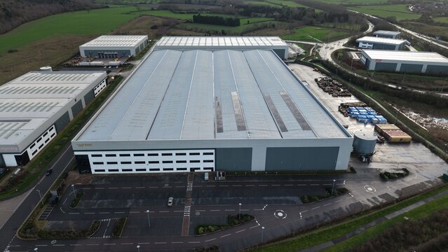 Tamworth, United Kingdom - 21 February 2026: Aerial view of Signet Way's industrial buildings, their roofs gleaming under the diffused light, surrounded by the muted greens of the landscape.
