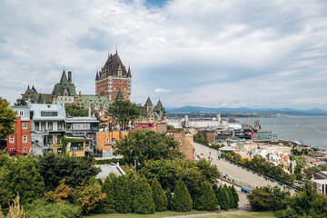Quebec City, Canada - August 23, 2025: Fairmont Le Chateau Frontenac castle hotel with turrets overlooking Terrasse Dufferin boardwalk, stone walls and tourists strolling on summer day © Andrei Antipov