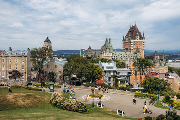 Quebec City, Canada - August 23, 2025: Fairmont Le Chateau Frontenac castle hotel with turrets overlooking Terrasse Dufferin boardwalk, stone walls and tourists strolling on summer day © Andrei Antipov