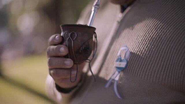 Argentine man holding traditional mate with national cockade on patriotic celebration day.