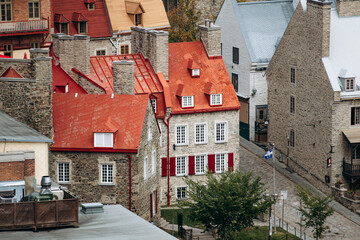 Quebec City, Canada - August 23, 2025: Aerial overview of Old Quebec stone houses with red, gray slate roofs, narrow streets, Quebec flags