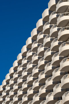 Architecture facade with balconies and windows on a residential apartment tower rising into open sky with pattern repetition and calm geometry in spain