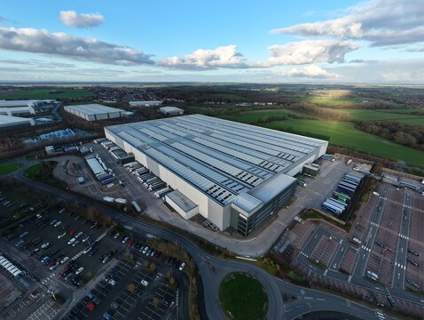 Tamworth, United Kingdom - 21 February 2026: Aerial view of LKQ Euro Car Parts (ECP) T2, a sprawling industrial landscape where metallic roofs meet concrete yards under a vast sky.
