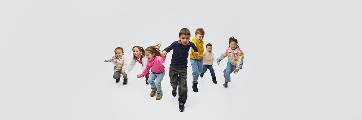 Group of children running toward camera wearing mid season kids fashion outfits in studio. Concept of seasonal children clothing promotion, kids apparel marketing and retail fashion campaign. Banner