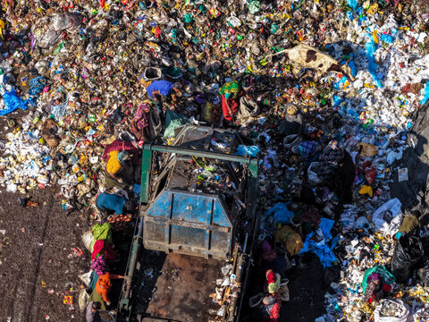 Chattogram, Bangladesh - 25 November 2025: Aerial view of Anondobazar Landfill's stark landscape where vibrant colors of clothing contrast with the muted tones of waste and machinery.