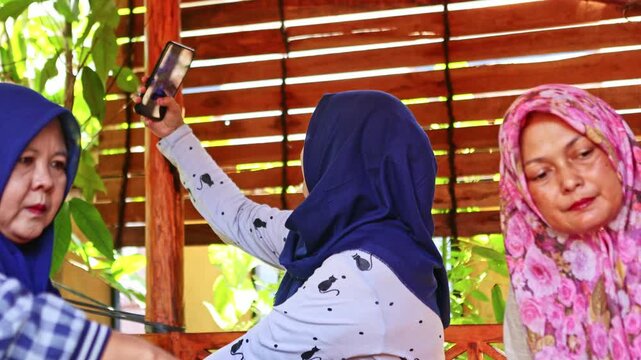 Indonesian muslim woman taking selfie with friends during celebration