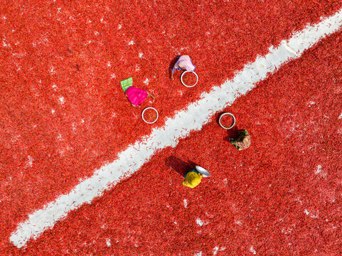 Aerial view of colorful objects scattered on a vibrant red surface intersected by a stark white line, Sariakandi, Rajshahi Division, Bangladesh.