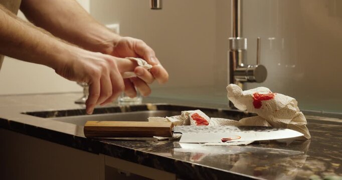 Close-up of a cooking mishap in a modern kitchen, showing a hand cut by a knife near the sink with visible bleeding, highlighting domestic safety risks and first aid awareness.