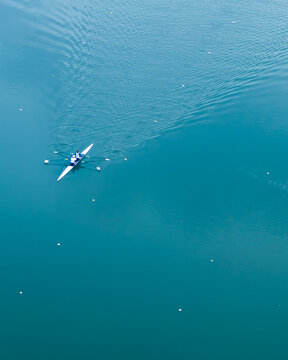 Aerial view of a lone rower cutting through the tranquil, turquoise waters of the River Thames, a serene dance of motion and stillness, Reading, Berkshire, United Kingdom.