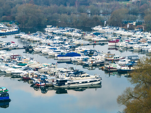 Aerial view of a marina crammed with boats reflecting the cloudy sky, a bustling scene of maritime activity near the Thames River, Reading, Berkshire, United Kingdom.