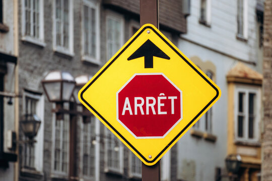 Yellow traffic warning sign with French stop sign Arret in Old Quebec