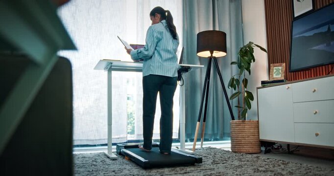 Laptop, document and woman with remote work on treadmill for client admin, fitness and productivity. Freelance PA, back of person and tech on walking machine for scheduling, wellness or below in home