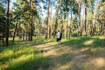 Young Friends Enjoying a Leisurely Walk Through a Scenic Pine Forest on a Bright Summer Afternoon