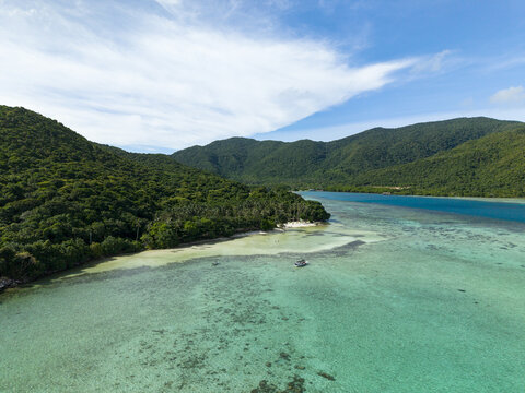 Aerial view of lush green hills cascading into the turquoise waters of Bobby Beach, Karimunjawa, Central Java, Indonesia.