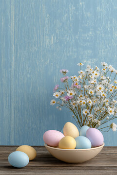 Retro Easter Table with Pastel Speckled Eggs in Bowl and White Daisy Bouquet on Rustic Wood Against Blue Wall
