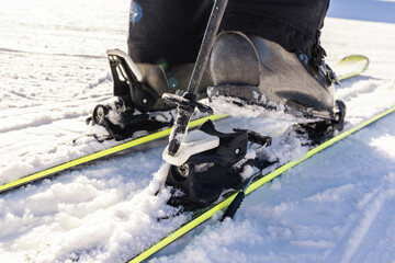 A man is wearing white ski boots in the snow. Ski boots with skis on a snowy slope. Active leisure.