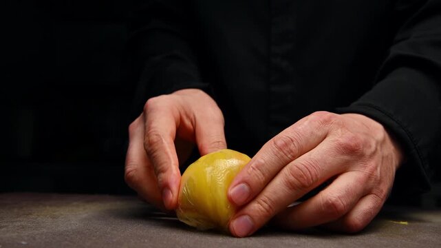 A chef rolls mango slices into a ball in plastic wrap.