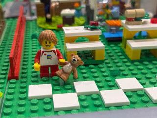 Naklejka premium Lego child with teddy on green baseplate