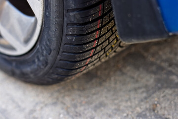A stack of new all season tires against the background of a passenger car, illustrating tire replacement in autumn or spring and all-season tires as an alternative to seasonal tires. © Robert