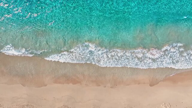 Aerial view of a sandy sea beach background. Looping ocean texture, aerial view of calmly moving ocean waves. Flying over a sandy beach and waves, seamless loop of a sunset beach.