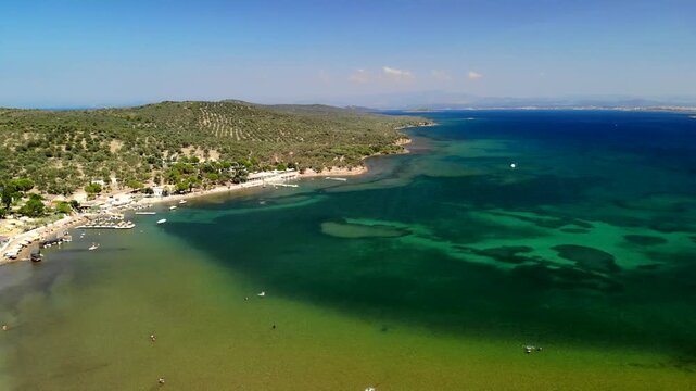 Aerial view of boats docked in the harbor, with the turquoise sea contrasting with the lush green coastline, Cunda Island, Ayvalik, Balikesir, Turkey.
