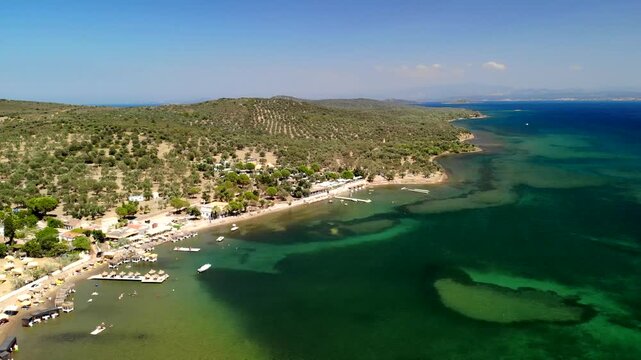 Aerial view of the coast with boats and clear green waters contrasting with the lush green hills, Cunda Island, Ayvalik, Balikesir, Turkey.