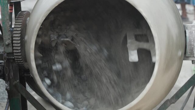 Concrete mixture is being prepared by machine with cement, sand and stone for casting.