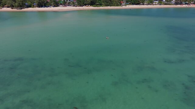 Expansive turquoise lagoon with tiny human figures emphasizing scale and tranquility.